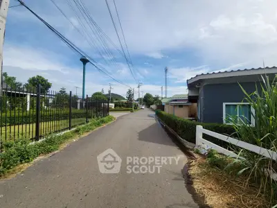 Charming suburban street view with lush greenery and cozy homes under a clear blue sky.