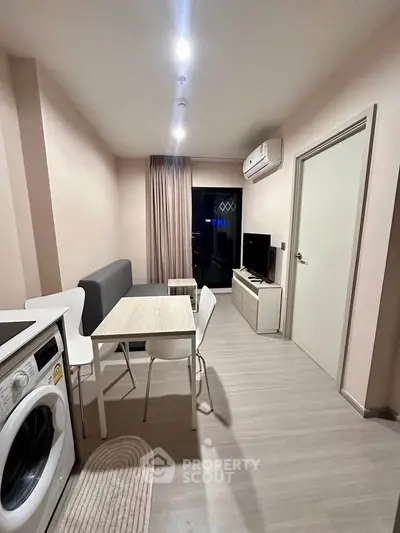 Modern living room with dining area and washing machine, featuring sleek furniture and air conditioning.