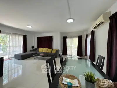 Spacious modern living room with large windows and elegant dining area