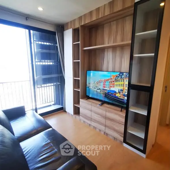 Modern living room with sleek furniture and built-in TV unit, featuring a balcony view.