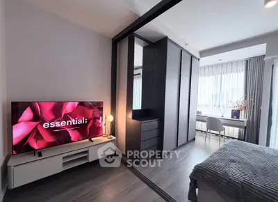 Modern bedroom with sleek design, featuring a large TV and ample natural light.