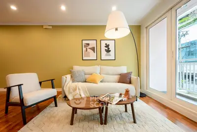 Chic living room with modern decor, cozy seating, and natural light from large windows.