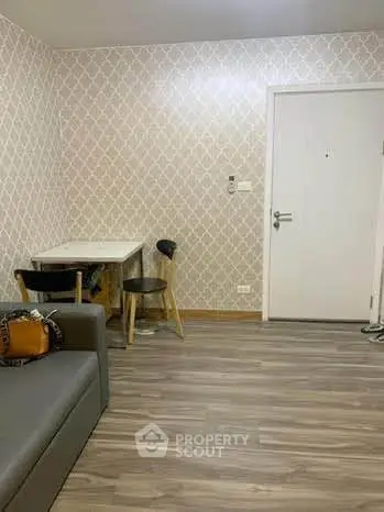 Modern living room with stylish wallpaper and wooden flooring, featuring a cozy seating area and a small dining table.