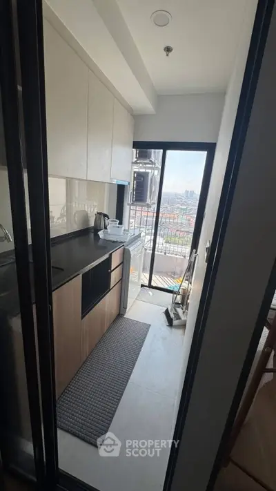 Modern kitchen with sleek cabinetry and balcony view in urban apartment