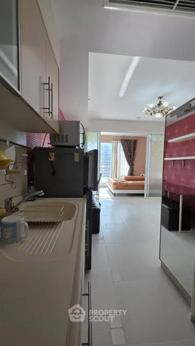 Modern open kitchen leading to a bright living area with large windows and stylish decor.