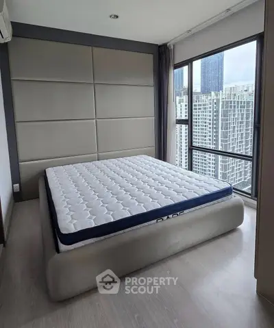 Modern bedroom with large windows offering stunning city views in a high-rise apartment.