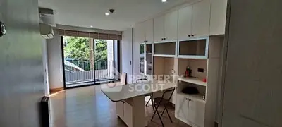 Spacious study room with built-in desk and cabinets, large window with balcony view.