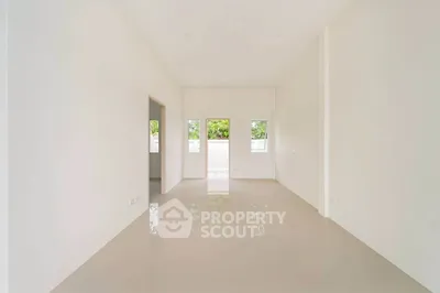Spacious empty room with glossy tiled floor and large windows offering natural light.