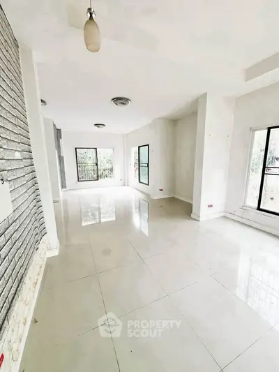 Spacious empty living room with large windows and modern lighting in a bright apartment.