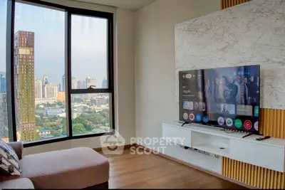 Modern living room with city view, large window, and wall-mounted TV in a stylish apartment.