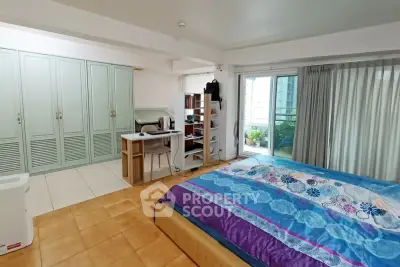 Spacious bedroom with large bed, built-in wardrobe, and balcony access in modern apartment.