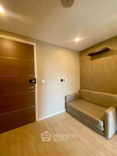 Cozy small living room with modern sofa and wooden door, perfect for compact spaces.