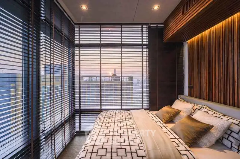 Luxurious bedroom with floor-to-ceiling windows offering stunning city views at sunset.