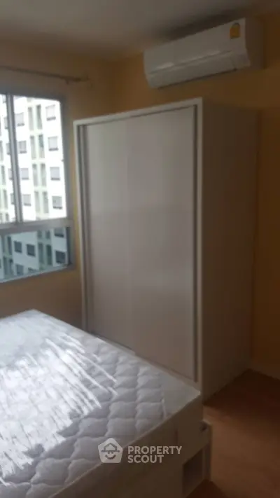 Cozy bedroom with large window and air conditioning in modern apartment