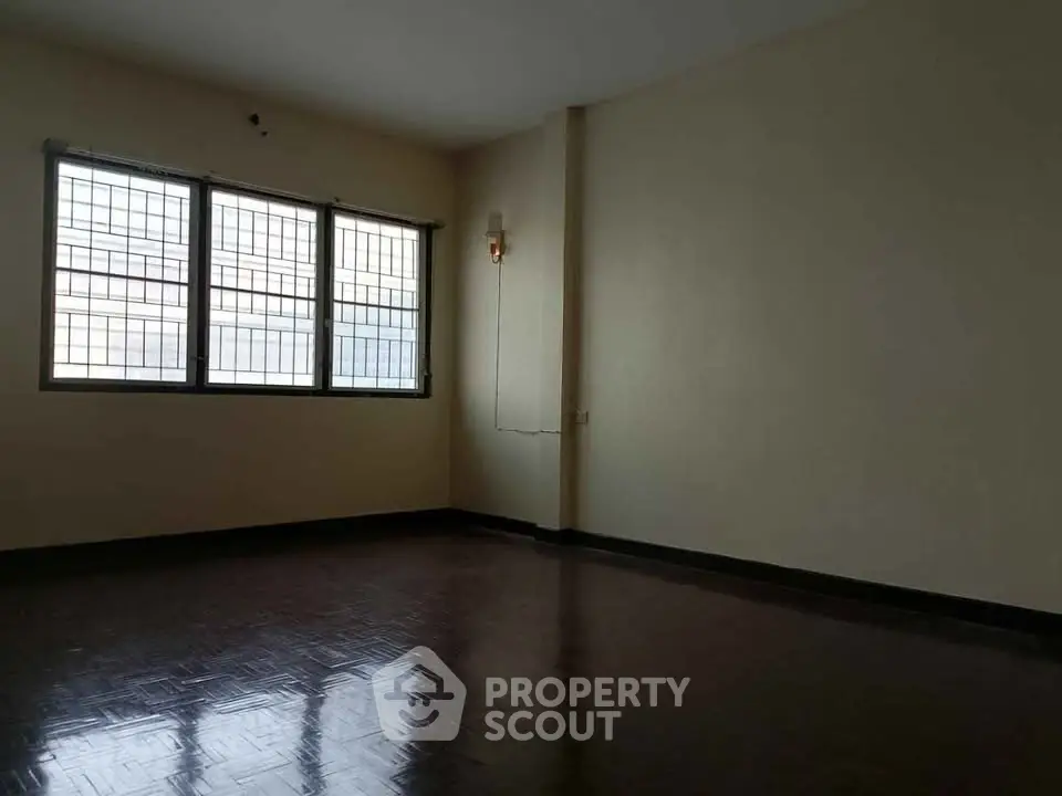 Spacious empty room with large windows and wooden flooring, ideal for customization.