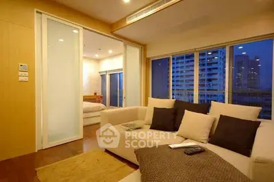 Modern living room with cozy sofa and city view, adjacent to a stylish bedroom.
