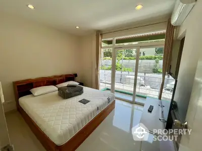 Bright bedroom with large windows and garden view, featuring modern furniture and air conditioning.