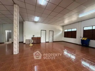 Spacious open-plan room with tiled flooring and ample natural light, ideal for versatile living arrangements.