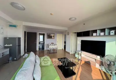 Spacious living room with modern decor and natural light, featuring a sleek TV setup and comfortable seating.