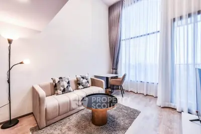 Modern living room with high ceilings, elegant sofa, and large windows offering natural light.