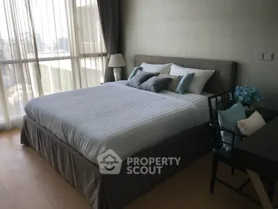 Spacious bedroom with large window and elegant decor in modern apartment.