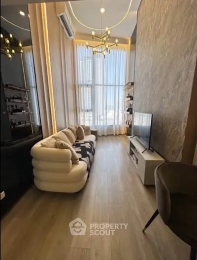 Luxurious modern living room with high ceilings, elegant chandelier, and floor-to-ceiling windows offering city views.