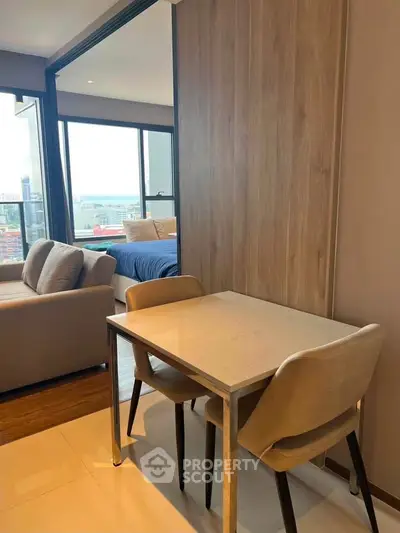 Modern apartment interior with cozy living area and bedroom view, featuring stylish furniture and large windows.