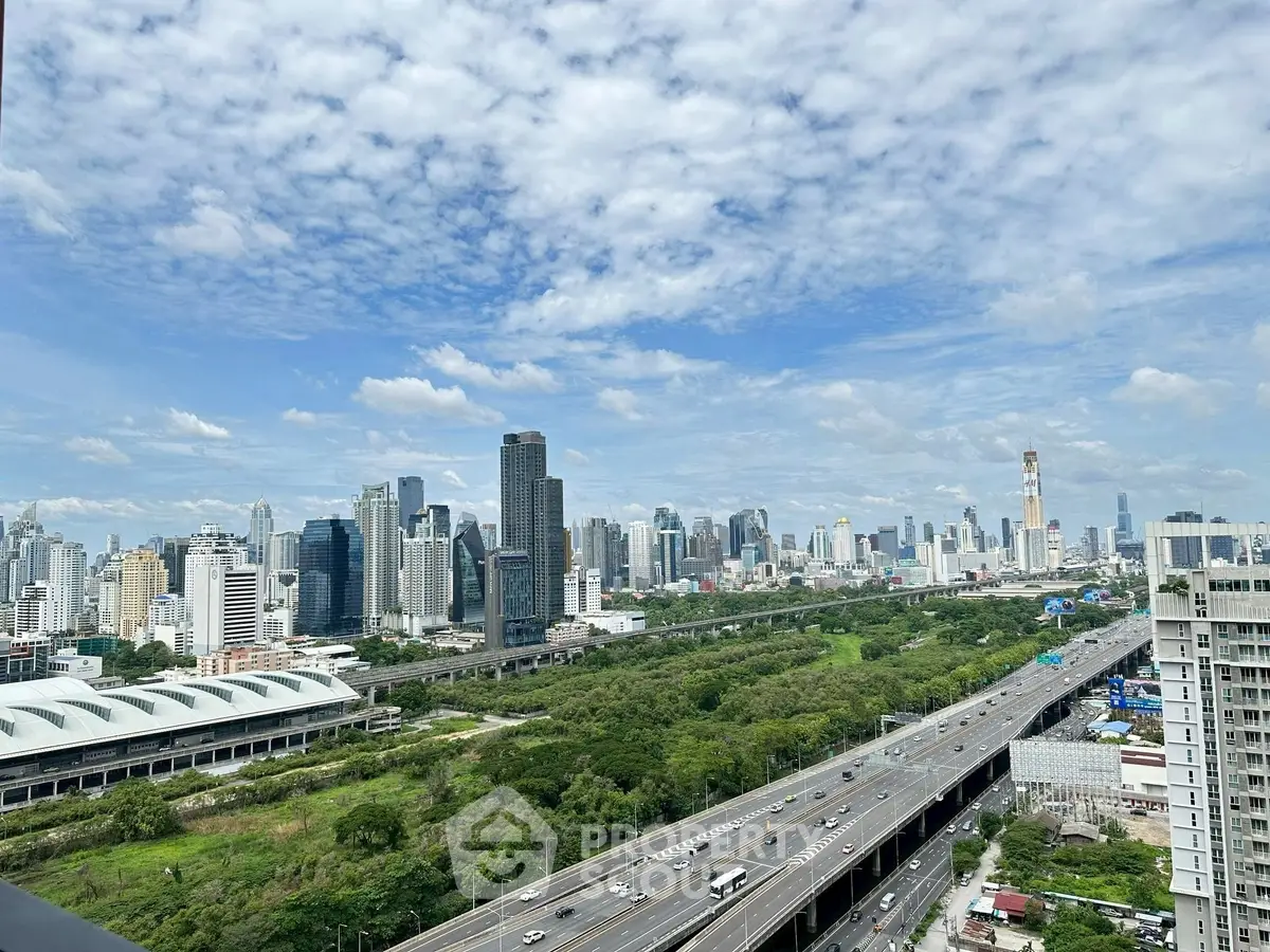 Stunning cityscape view from a high-rise balcony overlooking lush greenery and a bustling highway.
