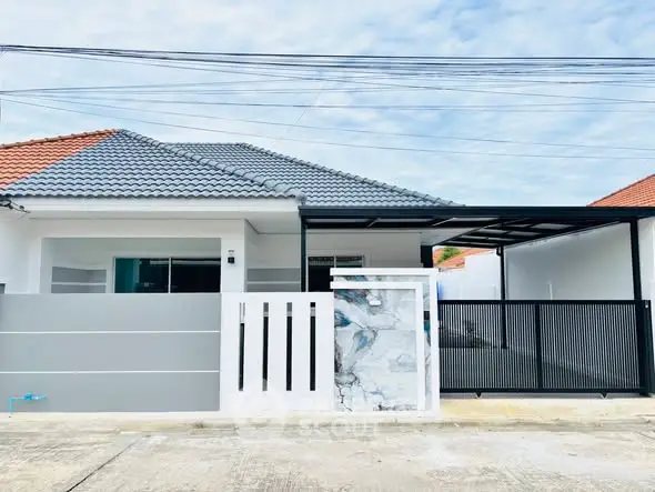 Modern single-story house with sleek design and gated entrance, featuring a tiled roof and spacious driveway.