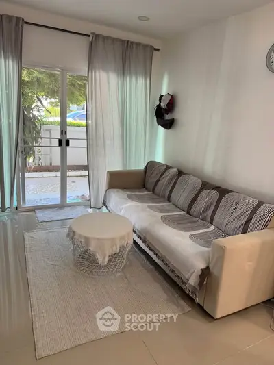 Cozy living room with modern sofa and natural light from large window, perfect for relaxation.