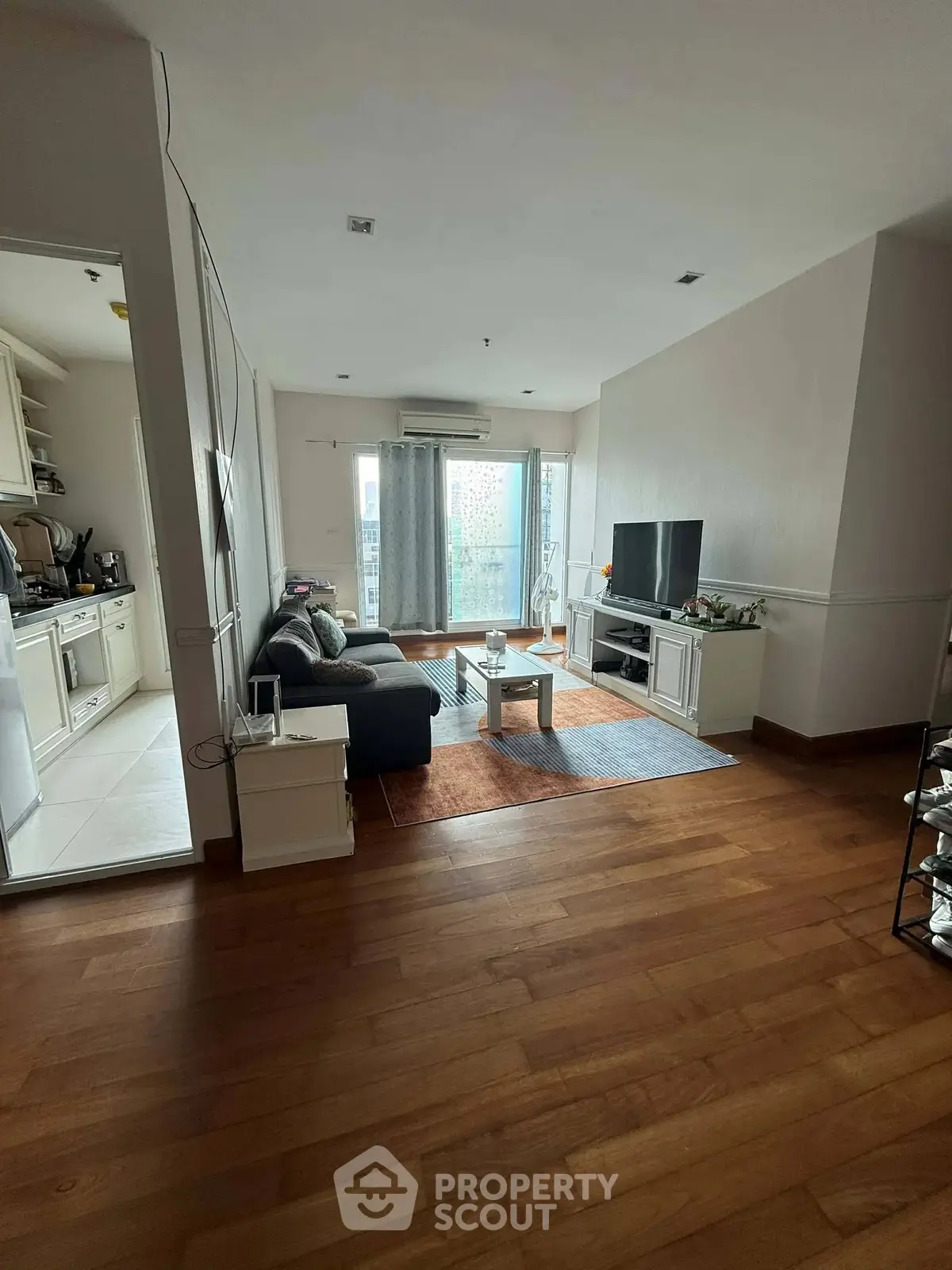 Spacious living room with wooden flooring and modern decor in a cozy apartment.