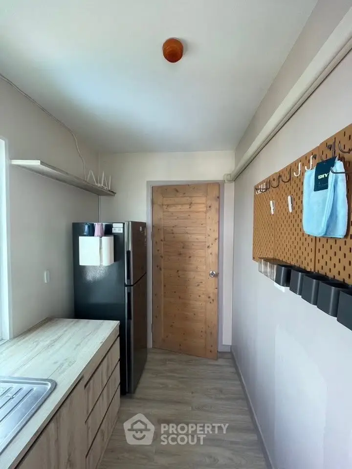 Modern kitchen with sleek cabinetry and black fridge, featuring a pegboard for organization.