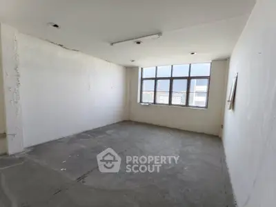 Spacious unfinished room with large window offering potential for customization.