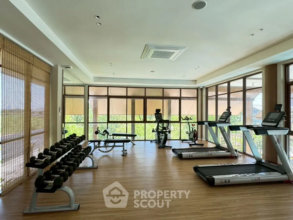 Spacious gym with modern equipment and large windows offering a scenic view.