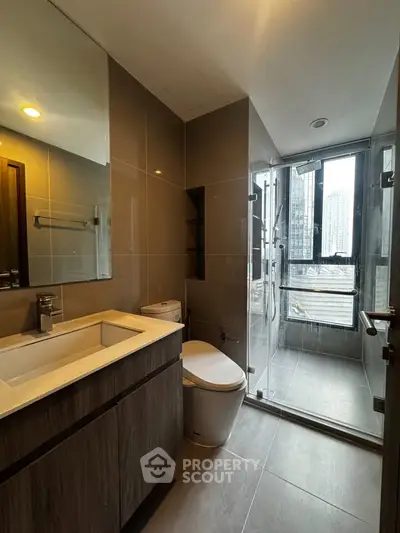 Modern bathroom with sleek fixtures and city view from glass shower enclosure.