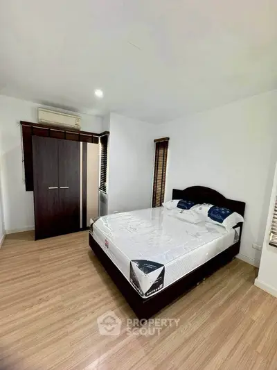 Spacious bedroom with wooden flooring and modern wardrobe in a cozy apartment.