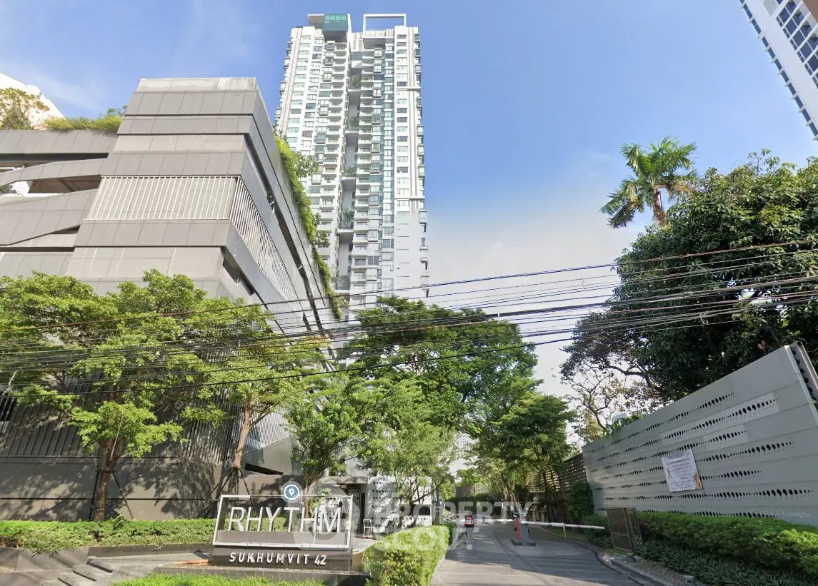 Modern high-rise building with lush greenery at Rhythm Sukhumvit 42 entrance.