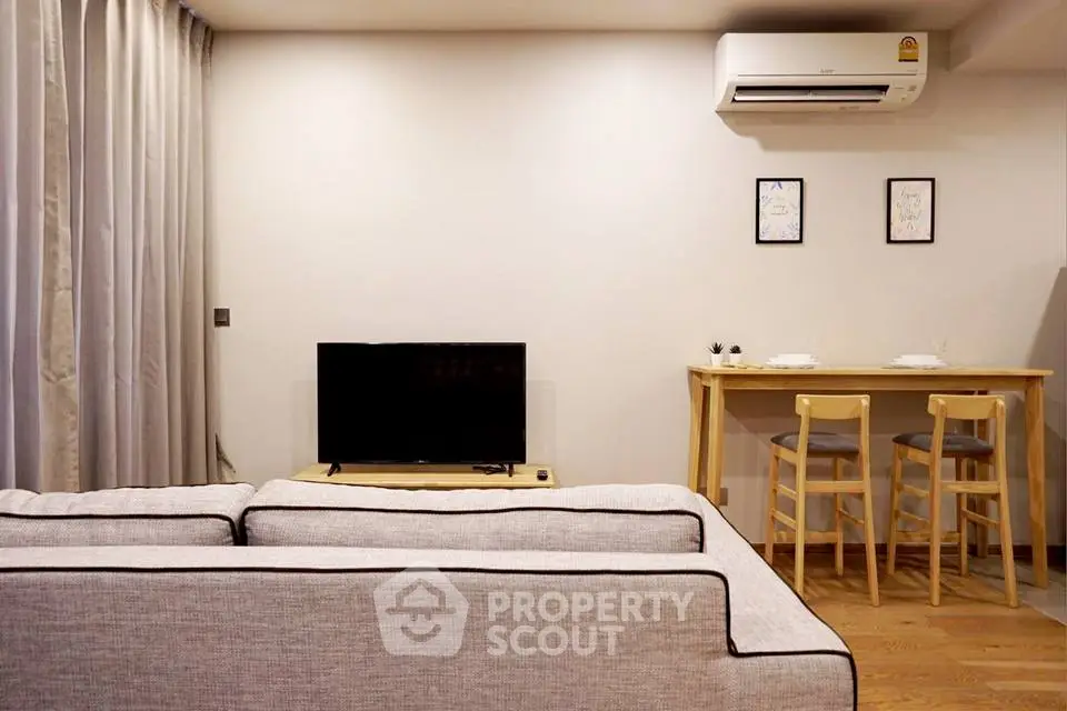 Modern living room with cozy sofa and dining area, featuring air conditioning and minimalist decor.