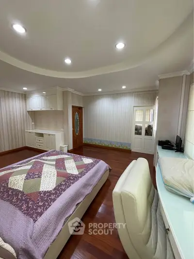 Spacious bedroom with elegant decor and wooden flooring, featuring a cozy bed and stylish furniture.