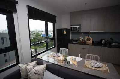 Modern kitchen with open layout and city view, featuring sleek cabinetry and dining area.