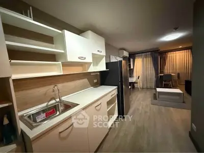 Modern open-layout kitchen with sleek cabinetry and spacious living area in stylish apartment.