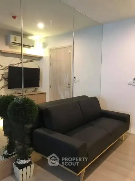 Modern living room with sleek black sofa and mirrored wall