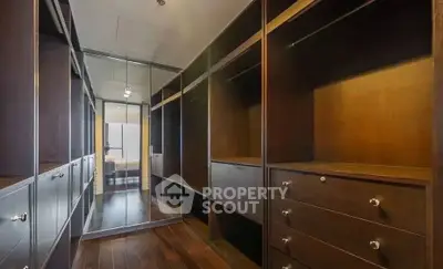 Spacious walk-in closet with elegant wooden shelving and mirrored doors.
