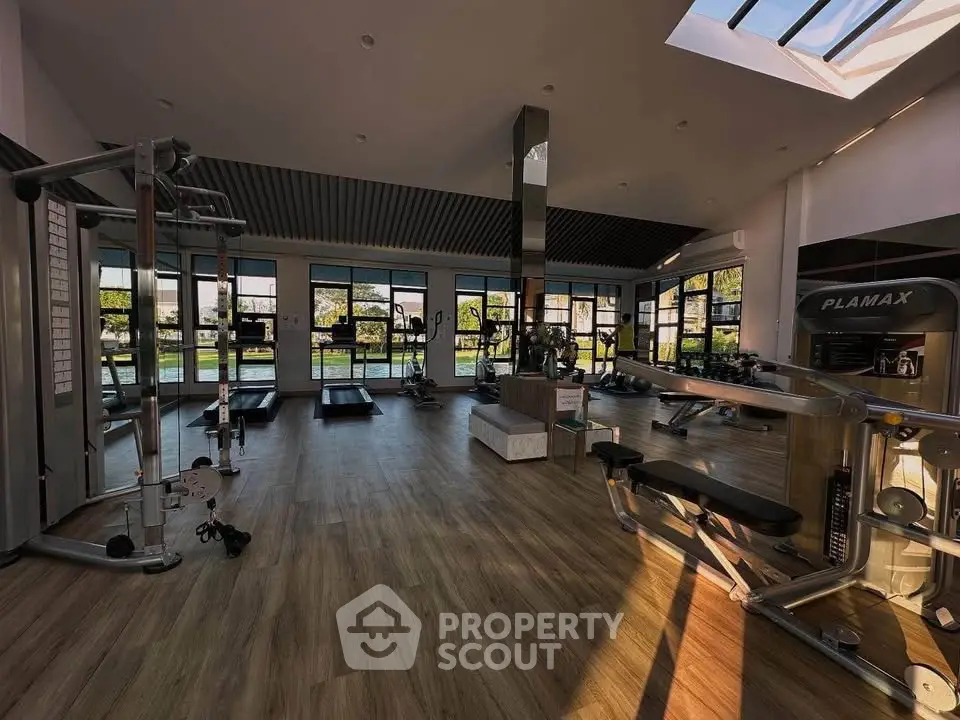Spacious modern gym with large windows and natural light, featuring state-of-the-art fitness equipment.