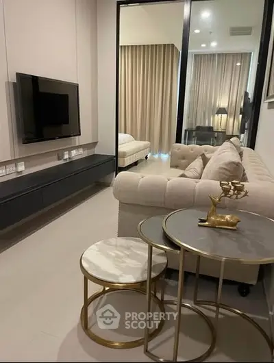 Modern living room with elegant sofa and nested tables, featuring a wall-mounted TV and stylish decor.