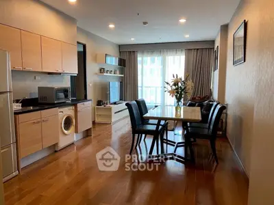 Spacious modern living room with open kitchen and dining area, featuring wooden flooring and natural light.