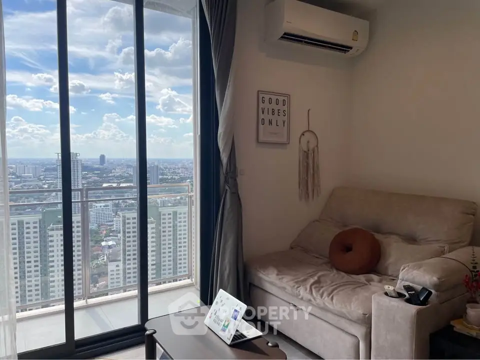 Cozy living room with stunning city view from high-rise balcony, featuring modern decor and air conditioning.