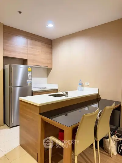 Modern kitchen with sleek design, featuring a stainless steel fridge and stylish breakfast bar.