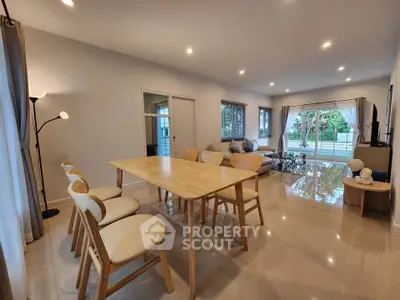 Spacious modern living room with elegant dining area and large windows offering garden views.