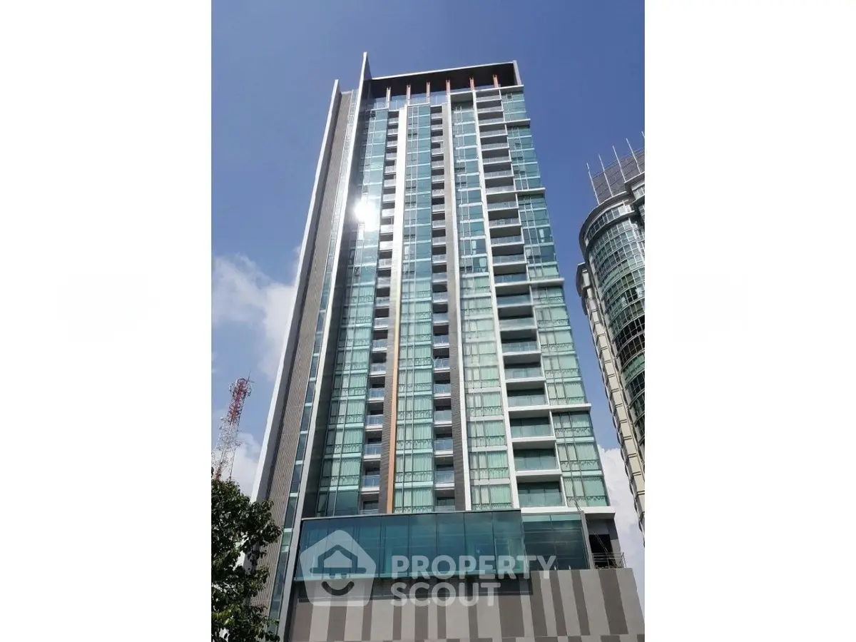 Modern high-rise building with glass facade and clear blue sky backdrop.